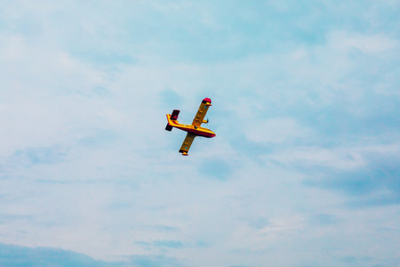 Small airplane. Yellow red Propeller plane is flying on blue sky