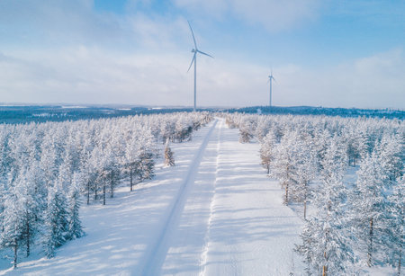 Aerial drone view of Wind turbines in winter landscape with snow covered trees and snow road in Finland, Europe. Alternative energy in winter.の写真素材