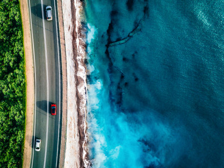 Aerial view of highway road with cars by turquoise ocean or sea water with waves. Beautiful summer landscape, vacation conceptの写真素材
