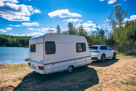 White trailer caravan car parked near blue lake, outdoor recreation at sea in summerの写真素材