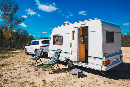 White trailer with a black and white checkered chair is parked in a field. The trailer is parked in a field with a clear blue sky above itの写真素材