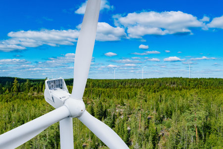 Wind turbine close-up. Aerial view of turbine winds or windmills in green summer woods in Finland....