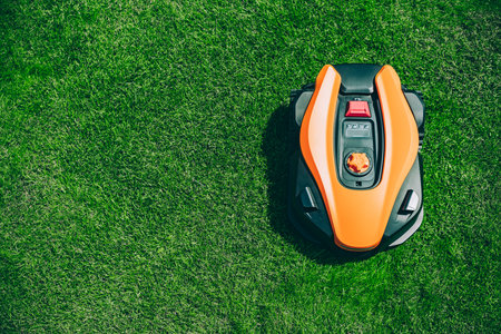 Automatic robotic lawn mower on a green lawn top view. Grass lawn mower robot in sunny summer day.の写真素材