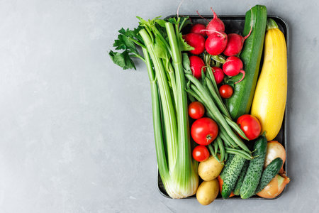 Variety of vegetables are displayed in a tray, including celery, cucumbers, and radishesの写真素材