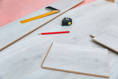 Tools and Materials Arranged for Flooring Installation with Measuring Tape, Ruler, Pencil, and Planks Displayed on a Surfaceの写真素材