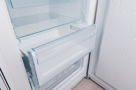 A Modern Refrigerator Interior Showcasing an Organized Transparent Vegetable Drawer and Empty Storage Space for Optimal Freshness and Convenienceの写真素材