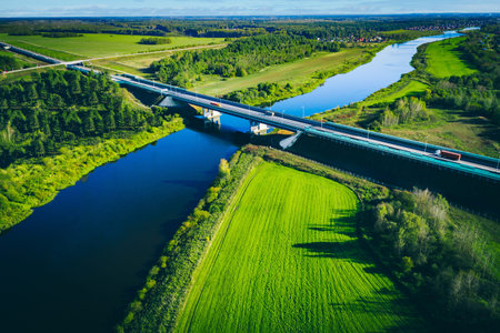 Aerial View of River, Bridge, and Lush Green Landscape Under a Clear Blue Skyの写真素材