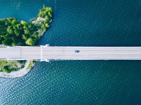 Aerial View of a Serene Bridge Connecting Land Surrounded by Crystal Clear Water and Lush Greeneryの写真素材