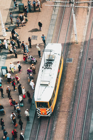A Busy Urban Scene with a Tram and Crowds of People Gathering at the Street Crossroads