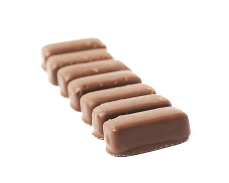 Line of chocolate coated candy bars isolated over the white backgroundの写真素材