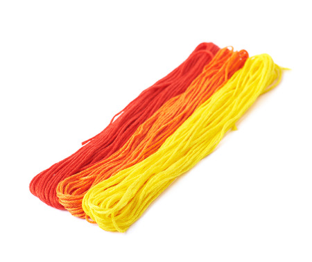 Red, orange, yellow colored embroidery thread yarns isolated over the white background