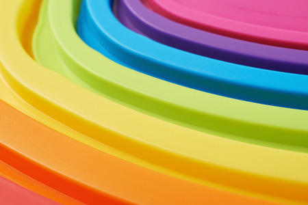 Stack of plastic food container rainbow colored caps as an abstract background composition