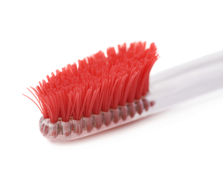 Well-worn transparent plastic toothbrush with a used red bristles isolated over the white background