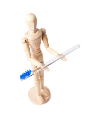 Human wooden mannequin doll figure holding a toothbrush, composition isolated over the white backgroundの写真素材