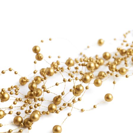 White surface covered with multiple golden garland beads thread decorations as an abstract background compositionの写真素材