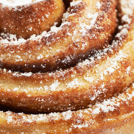 Close-up macro fragment of a cinnamon roll bun coated with the sugar powderの写真素材