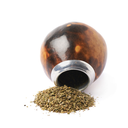 Calabash gourd vessel on top of a pile of dry mate tea leaves, composition isolated over the white backgroundの写真素材