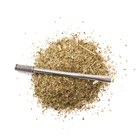 Pile of dry mate tea leaves with the bombilla drinking straw over it, composition isolated over the...