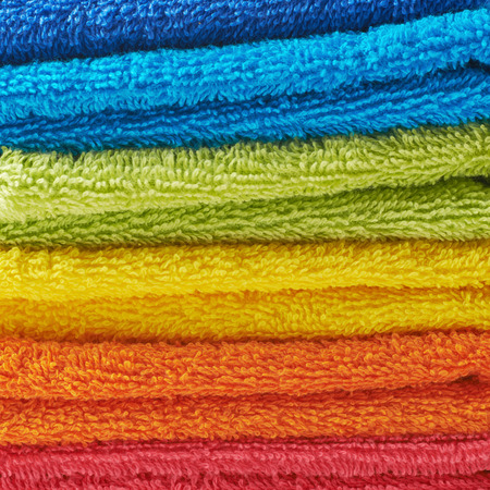 Pile of multiple rainbow colored towels, close-up fragment as a background texture compositionの写真素材