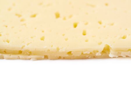 Close-up fragment of a cheese slice isolated over the white background as a backdrop compositionの写真素材