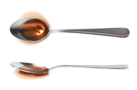 Steel spoon in a puddle of wine vinegar isolated over the white background, set of two different foreshorteningsの写真素材