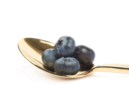Golden spoon full of bilberries isolated over the white backgroundの写真素材