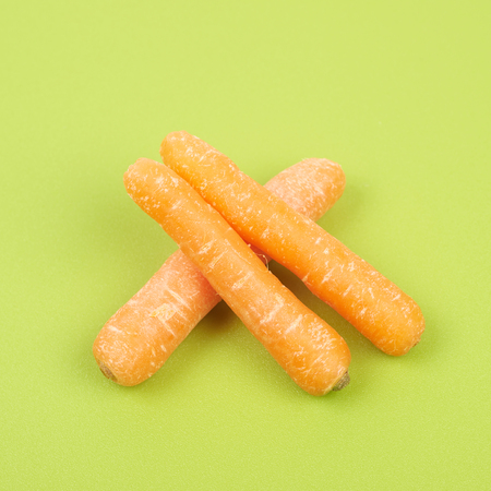 Baby carrots on a green plastic cutting board, close-up fragment compositionの写真素材