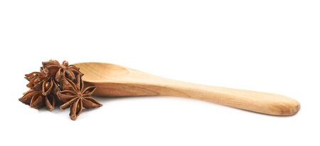 Chinese star anise seed served in a wooden spoon, composition isolated over the white background