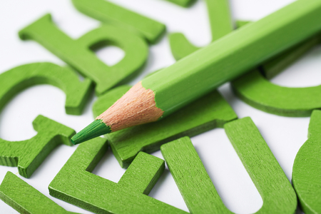 White surface covered with the multiple colorful painted wooden letters with the drawing pencil over it, composition as a backdrop compositionの写真素材