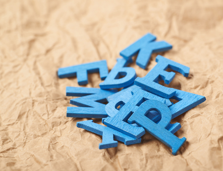 Pile of wooden letters over the crumbled paper surface as a backdrop compositionの写真素材