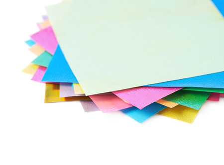 Twisted pile of multiple colorful origami paper sheets isolated over the white background, close-up crop fragment compositionの写真素材