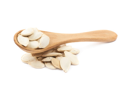 Pile of pumpkin seeds with the wooden spoon over it, composition isolated over the white backgroundの写真素材