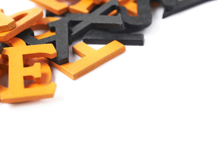 Pile of black and orange painted wooden letters isolated over the white backgroundの写真素材