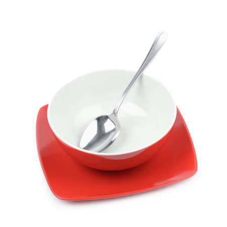 Red and white empty ceramic bowl over a square plate with a steel spoon in it, composition isolated over the white backgroundの写真素材