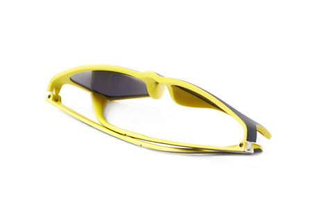 Pair of yellow plastic sunglasses with the dark shades, composition isolated over the white...
