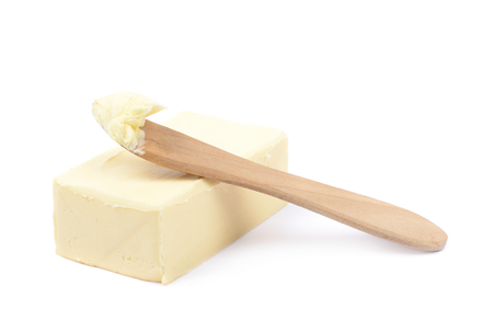 Wooden knife over a briquette piece of a butter, composition isolated over the white backgroundの写真素材