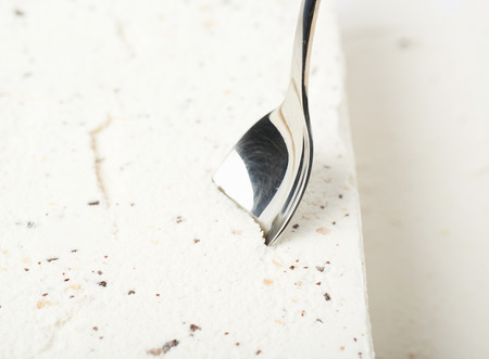 Close-up crop frament of a spoon in a chocolate chip vanilla ice cream's surfaceの写真素材