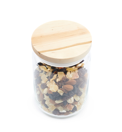 Glass kitchen jar filled with the mix of nuts and dried fruits, composition isolated over the white backgroundの写真素材
