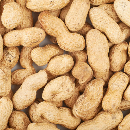 Close-up crop of a surface coated with the peanuts as a food backdrop composition