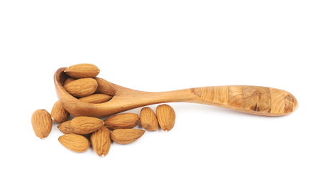 Pile of almond nuts with the wooden spoon over it, composition isolated over the white backgroundの写真素材