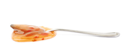 Splash of sweet and sour chilli sauce with the serving spoon over it, composition isolated over the white backgroundの写真素材