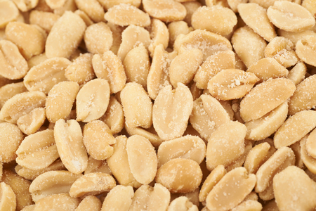 Close-up crop fragment of a surface coated with the salted peanuts as a backdrop texture compositionの写真素材