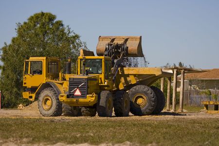 A front end loader filling the bed of a dump truck