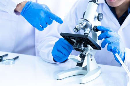 Close up Male researcher or Scientist looking through microscope in Central laboratory. Laboratory research concept.の写真素材