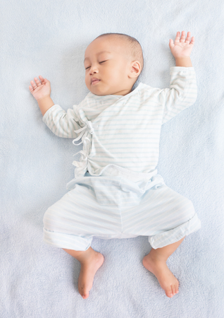 Sleeping baby on back on white bed