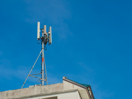 Mobile antenna in the roof of a building, against blue skyの写真素材