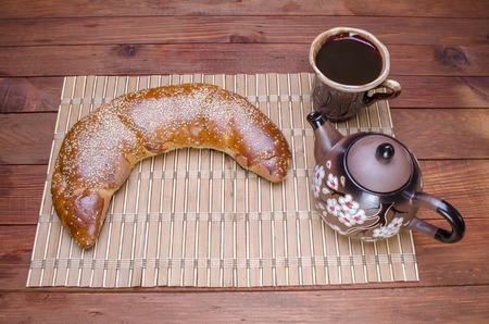 glass of milk with a magnificent roll on a wooden table