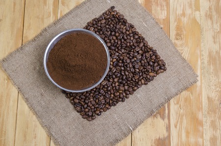 coffee grains scattered on a sacking on a wooden tableの写真素材