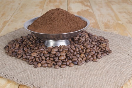 coffee grains scattered on a sacking on a wooden tableの写真素材