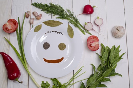 white plate with seasonings and greens on a wooden tableの写真素材